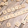 Wooden letter tiles spell 'rising inflation' symbolizing economic concerns.