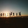 Silhouette of a group of friends jumping on a beach at sunset, expressing joy and freedom.